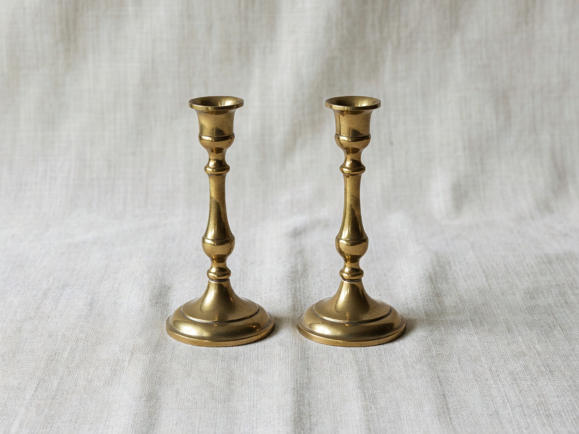 Pair of turned brass candlesticks on a linen surface
